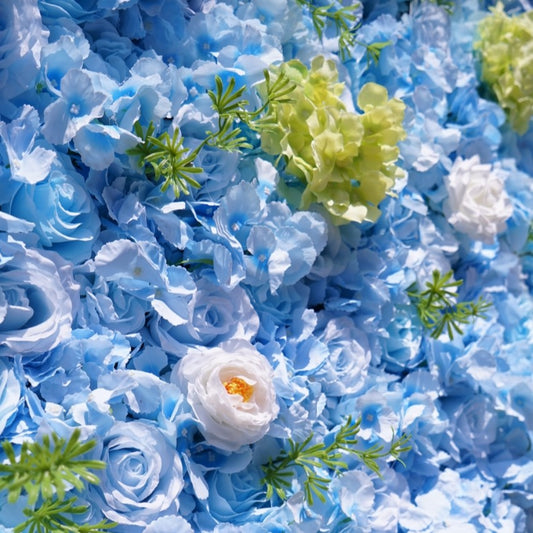Artificial flowers including blue and white roses and green leaves on a blue background.