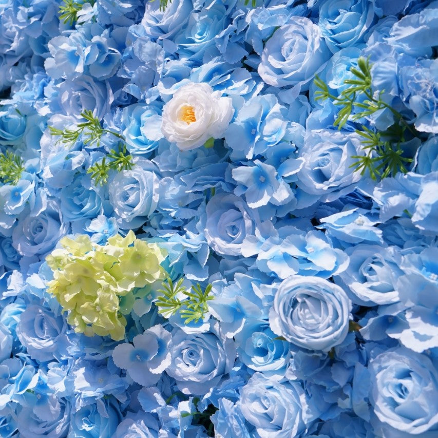 Wall of blue artificial flowers with a few white and green ones
