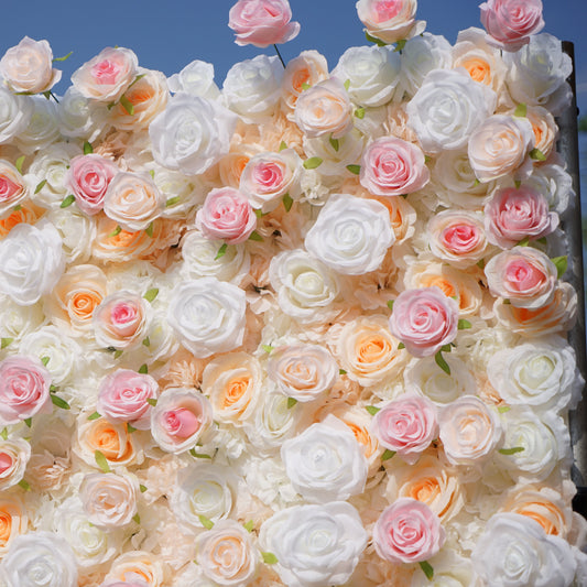 Wall of artificial flowers in pink, white, and peach colors against a blue sky.