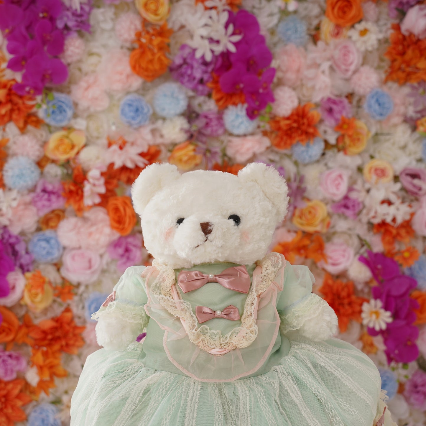 The bear is placed in front of the light pink flower wall to look lively and bright.