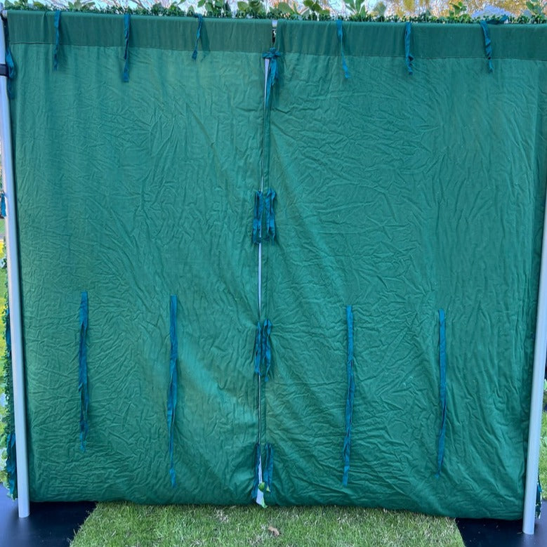 The green leaves and white rose fabric flower wall is fixed to a green cloth.