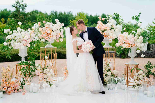 A newlywed couple standing in front of a row of flowers