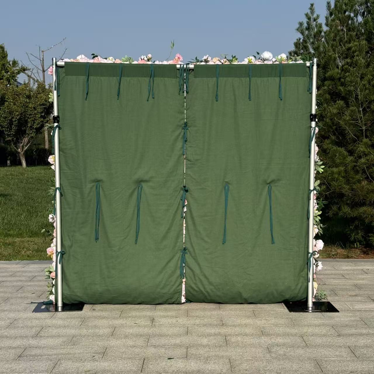 Green privacy screen with floral decorations on a paved area with trees in the background