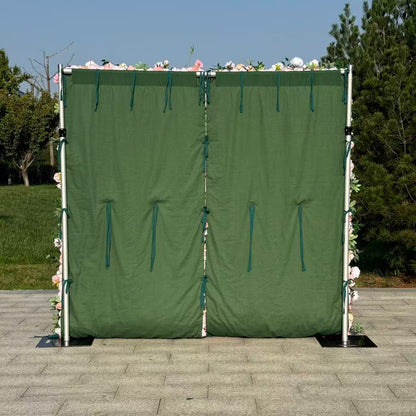 Green privacy screen with floral decorations on a paved area with trees in the background