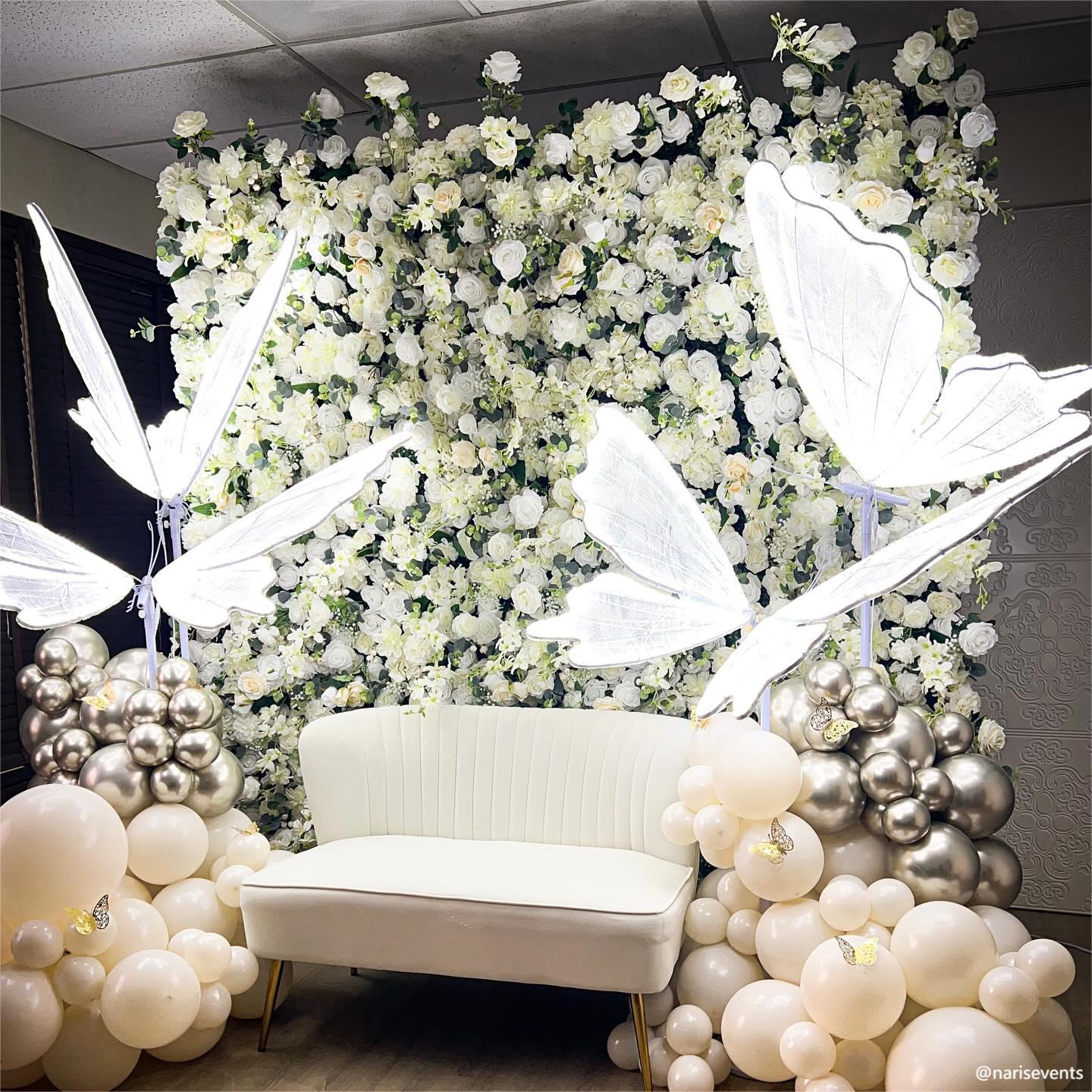 Butterfly ornaments make the white champagne flower wall looks more sophisticated and elegant.
