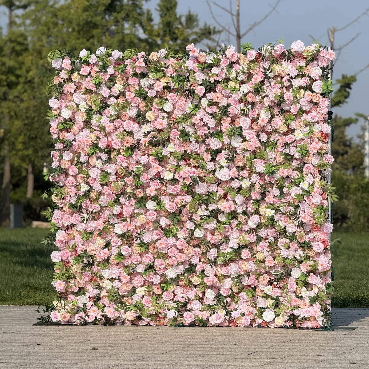 Floral wall with pink and white flowers on a wooden platform outdoors.