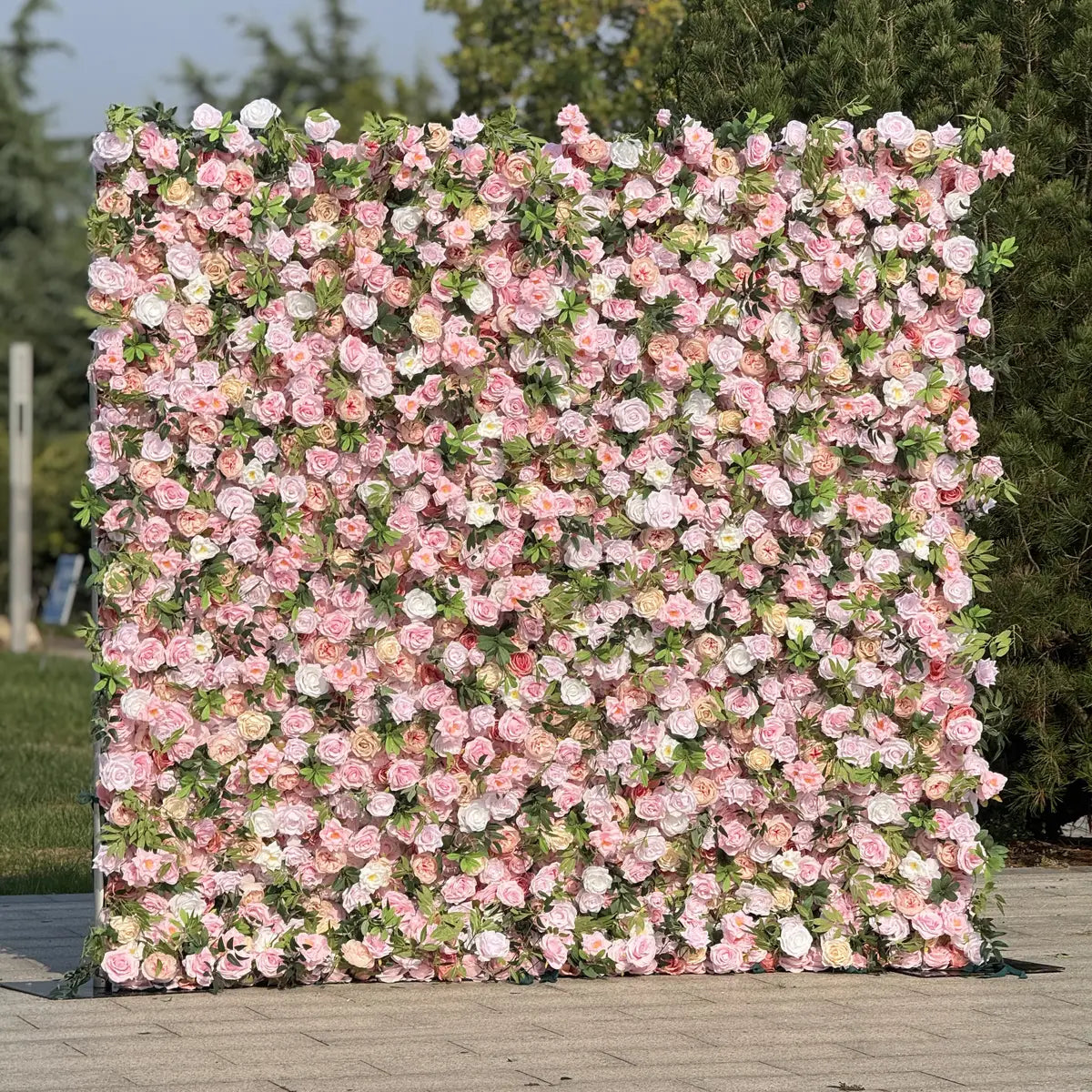 Floral wall with pink and white flowers on a wooden floor with greenery in the background