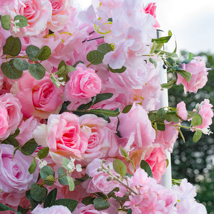 Pink floral arrangement with green leaves against a blurred natural background