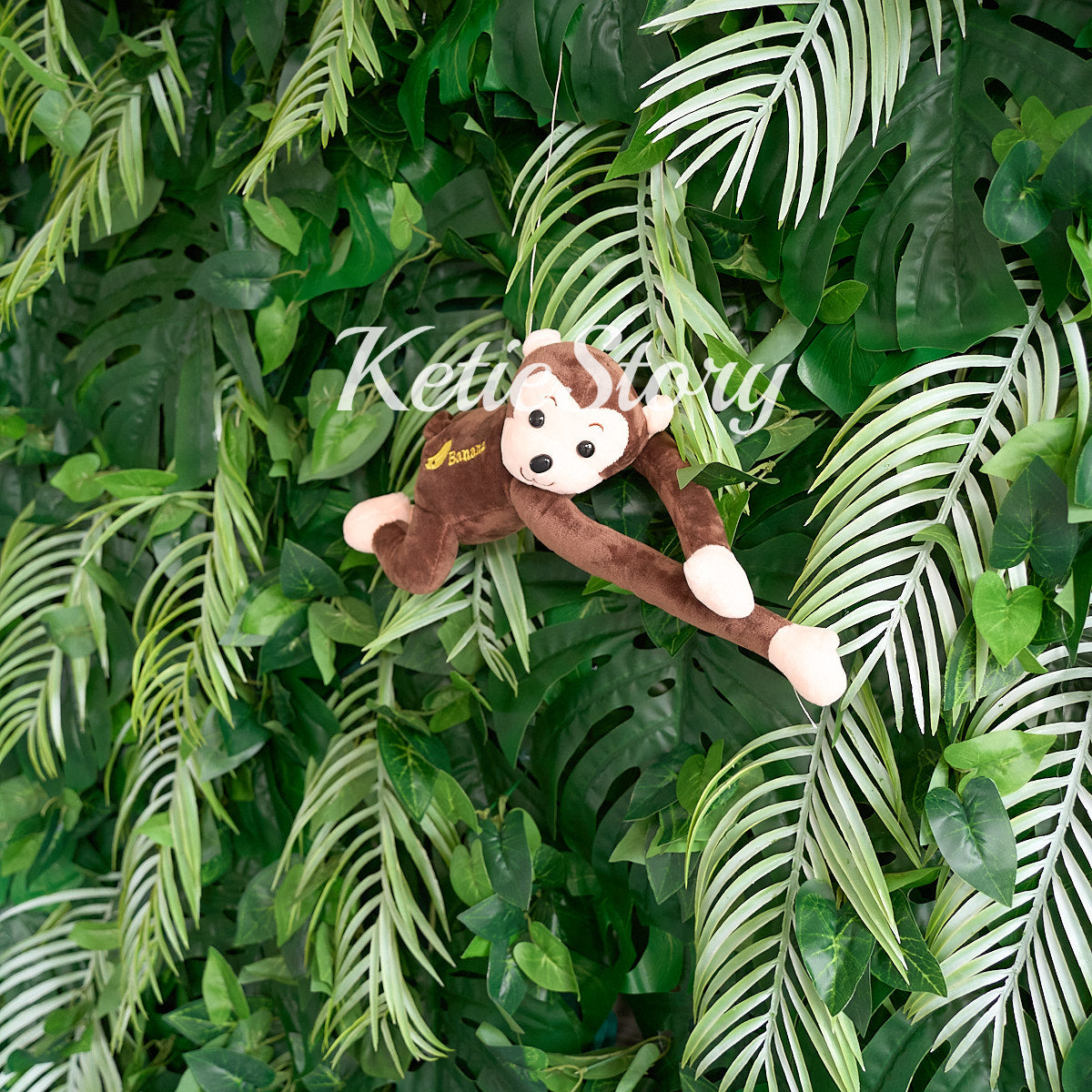 The monkey dolls add a tropical touch to the rainforest fabric flower wall.